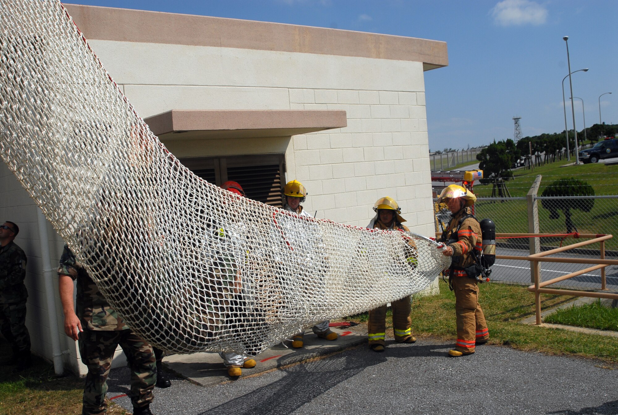 Senior Airman Alisha Depsey, 18th Operations Support Squadron, is greeted by members of the 18th Civil Engineering Squadron fire department as she arrives at the bottom of the Baker Life Chute. The control tower staff used the chute as an emergency exit during a simulated fire during exercise Beverly High 08-01 here Oct. 22.  (U.S. Air Force photo/Staff Sgt. Christopher A. Marasky)