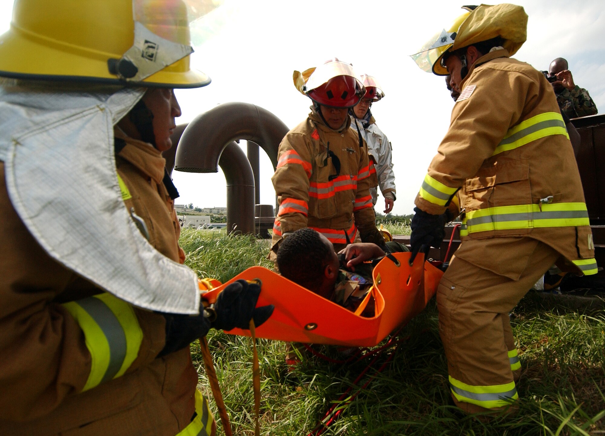 Airmen from the 18th Civil Engineer Squadron fire department carry an unconscious "victim" to safety during the Local Operational Readiness Exercise here Oct. 22. In the scenario an explosion at a fuel farm caused injuries to several people.  (U.S. Air Force photo/Tech. Sgt. Rey Ramon)