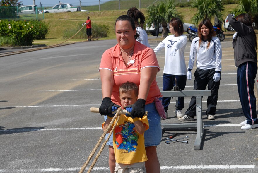 Anne Deguchi and her son, Logan, pull a rope out to connect it to machines that will coil three such ropes into one larger one Oct. 20.  Members of Team Kadena volunteered to participate in making a 100 meter long rope to be used for a tug-of-war at the upcoming Okinawa City International Carnival.  (U.S. Air Force photo/Staff Sgt. Christopher A. Marasky)