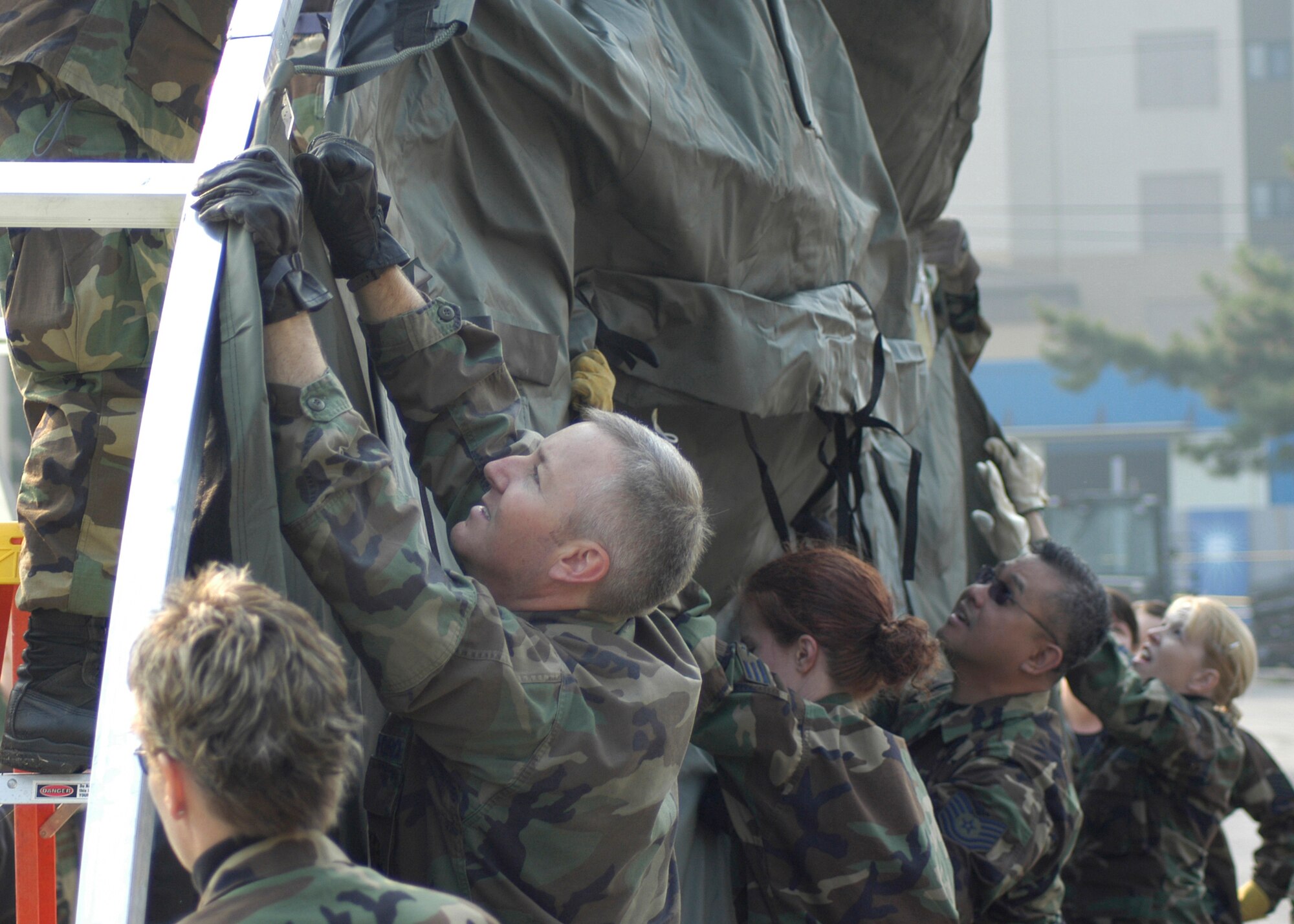 KUNSAN AIR BASE, South Korea-- Airmen from the 944th Medical Squadron, Air Force Reserve, place a front door tarp on the frame of a medical tent here Oct 23. Airmen from the 944th Medical Squadron and other Reservists from the 10th and 4th Air Forces are deployed to Kunsan AB to receive Expeditionary Medical System (EMEDS) training. (U.S. Air Force photo/Staff Sgt. Araceli Alarcon)                                