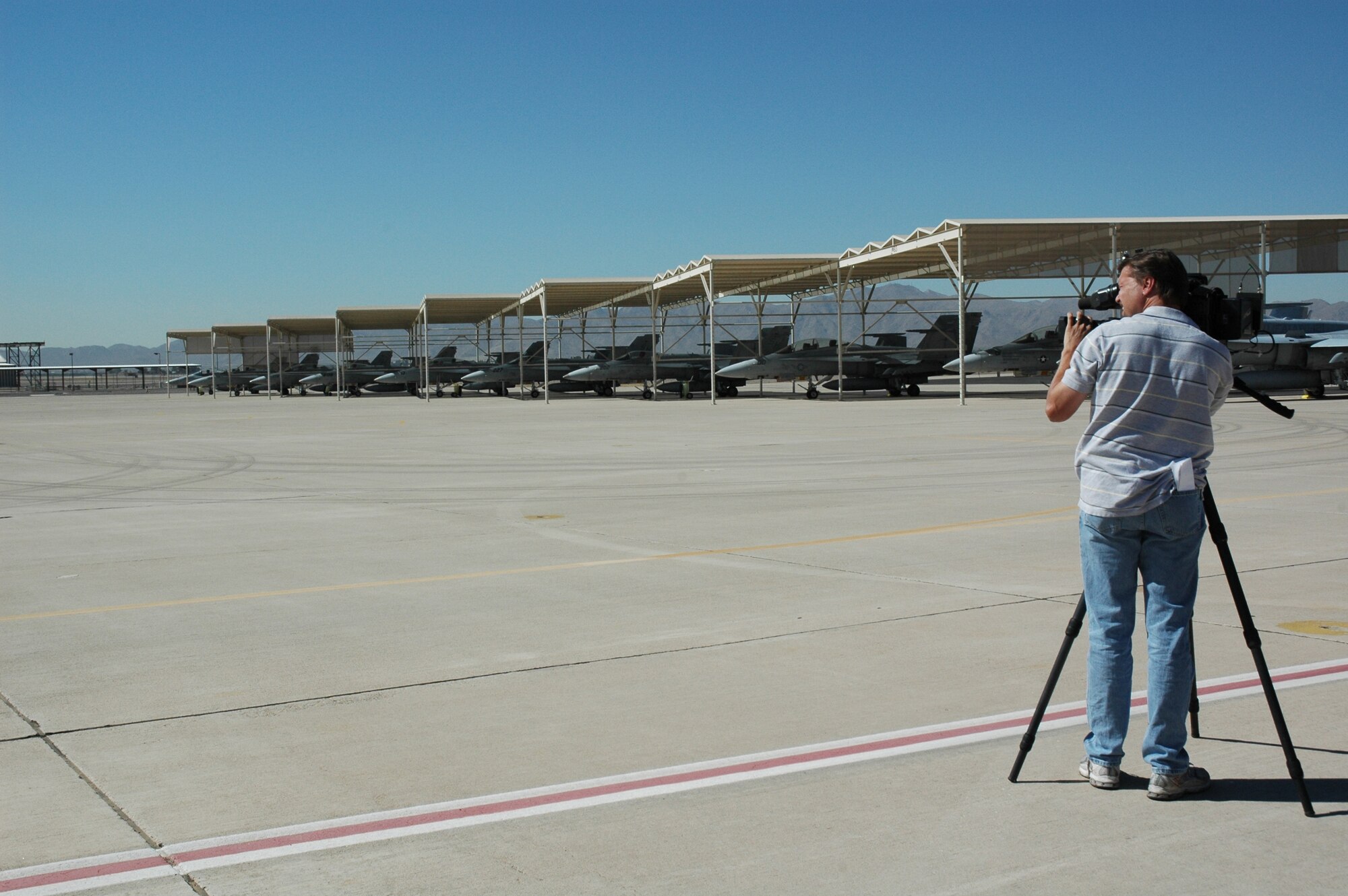 A local news crew gets video footage Oct. 23 of the F/A-18s from Marine Corps Air Station Miramar, Calif., parked on the flightline outside the 944th Fighter Wing. MCAS Miramar and the 3rd Marine Aircraft Wing evacuated 30 aircraft to Luke Air Force Base, Ariz., Oct. 22, due to the close proximity of wildfires raging in California. The squadron of F/A-18s is just one of six from Miramar evacuated to bases in Arizona and California. The aircraft will remain at these locations until the U.S. Marine Corps determines it is safe to return to their home station. While some aircraft are being evacuated, there are numerous heavy and medium lift helicopters remaining at Miramar to support the fire fighting operations. (U.S. Air Force photo/Tech. Sgt. Susan Stout)