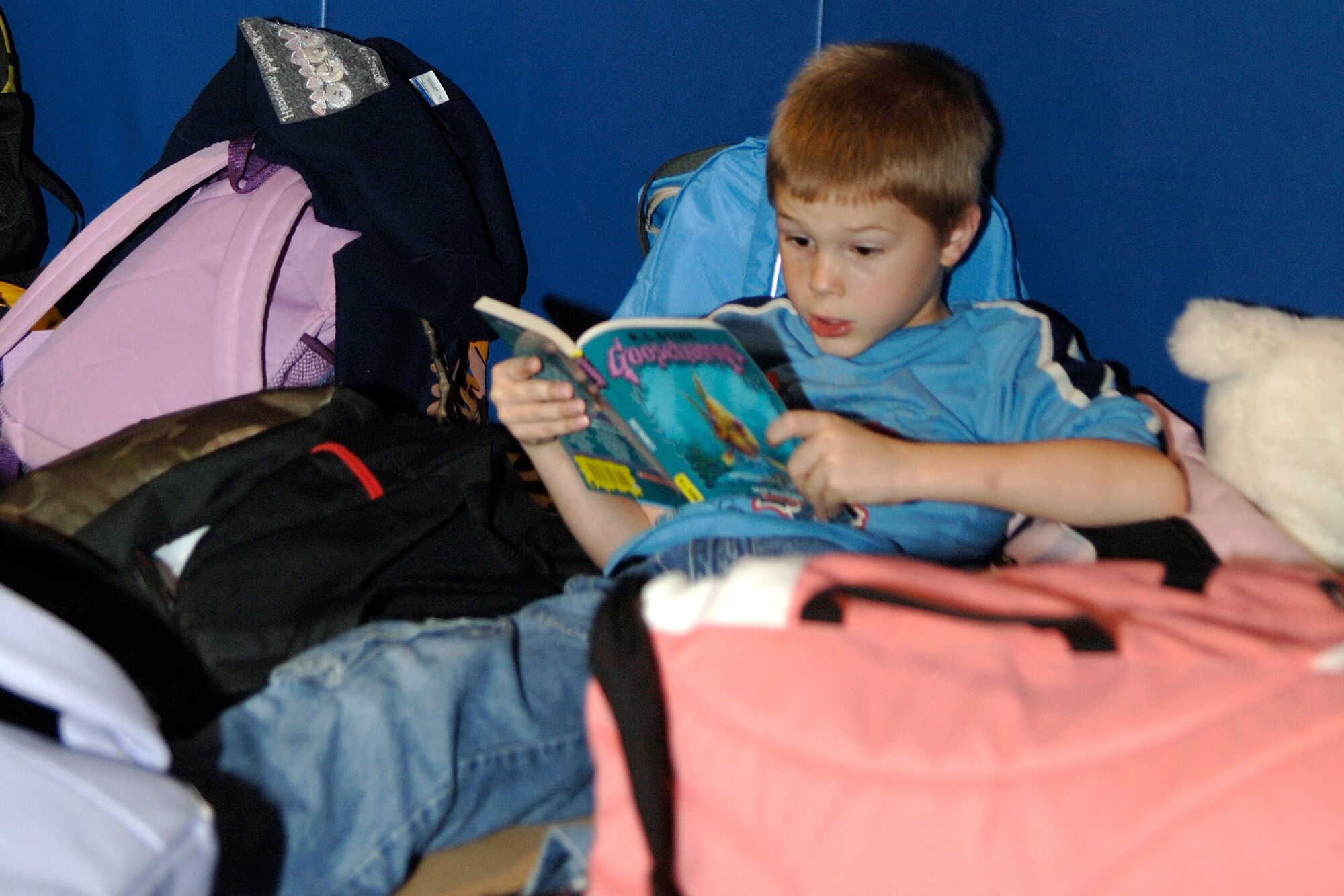 HANSCOM AFB, Mass. -- Orion Griffin, school age program, sits among backpacks to read a hair-raising story at the Base Youth Center during the Lights on Afterschool event Oct. 18. (U.S. Air Force photo by Jan Abate)

