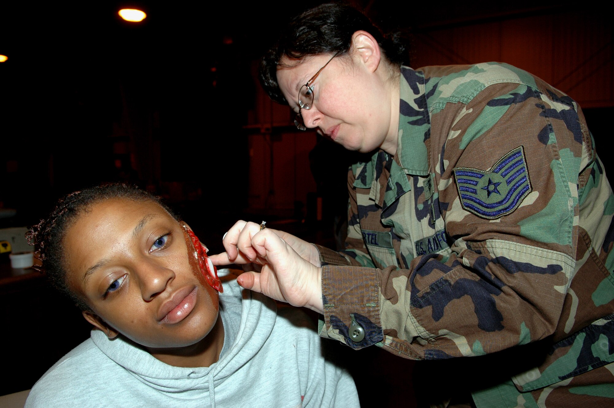 GRISSOM AIR RESERVE BASE, Ind., -- Tech. Sgt. Alicia Bartel, 434th Aerospace Medicine Squadron, applies moulage to Senior Airman Kellin McCamey, a survival equipment apprentice with the 434th Maintenance Squadron, prior to the start of an exercise Oct. 23. The makeup is designed to appear as wounds and add realism to the exercise scenario. (U.S. Air Force photo/Tech. Sgt. Doug Hays)