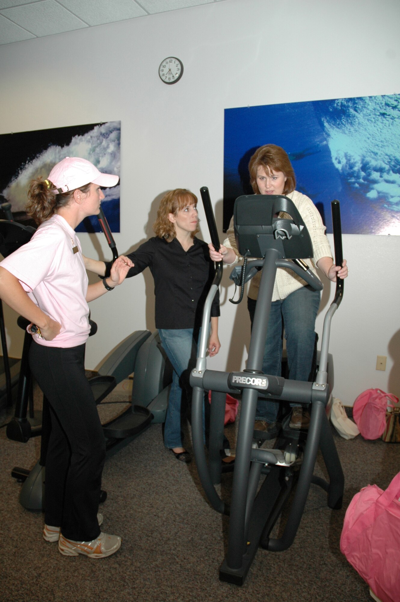 Kelley Suggs, health education program manager at the Health and Wellness Center, explains how to use equipment to Kim Tomlin and Sara Phillips during Ladies Night at the HAWC Oct. 19. Ladies Night at the HAWC is an event focusing on women's health, as well as breast cancer awareness. (U.S. Air Force photo/Airman 1st Class Emerald Ralston)