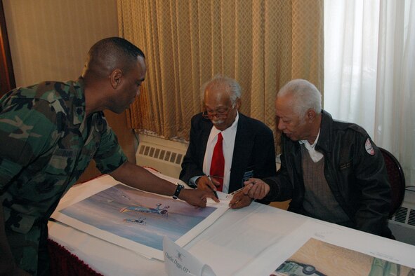 From left, Lt. Col. Edwin Daniel, Staff Judge Advocate, has a poster signed by Charlie Diggs and Harvey Sanford, both Original Tuskegee Airmen, during a reception held at the club by the Tuskegee Airmen, Hanscom Chapter, in celebration of the Air Force’s 60th Anniversary. (U.S. Air Force Photo by Dennis Lewis.)
