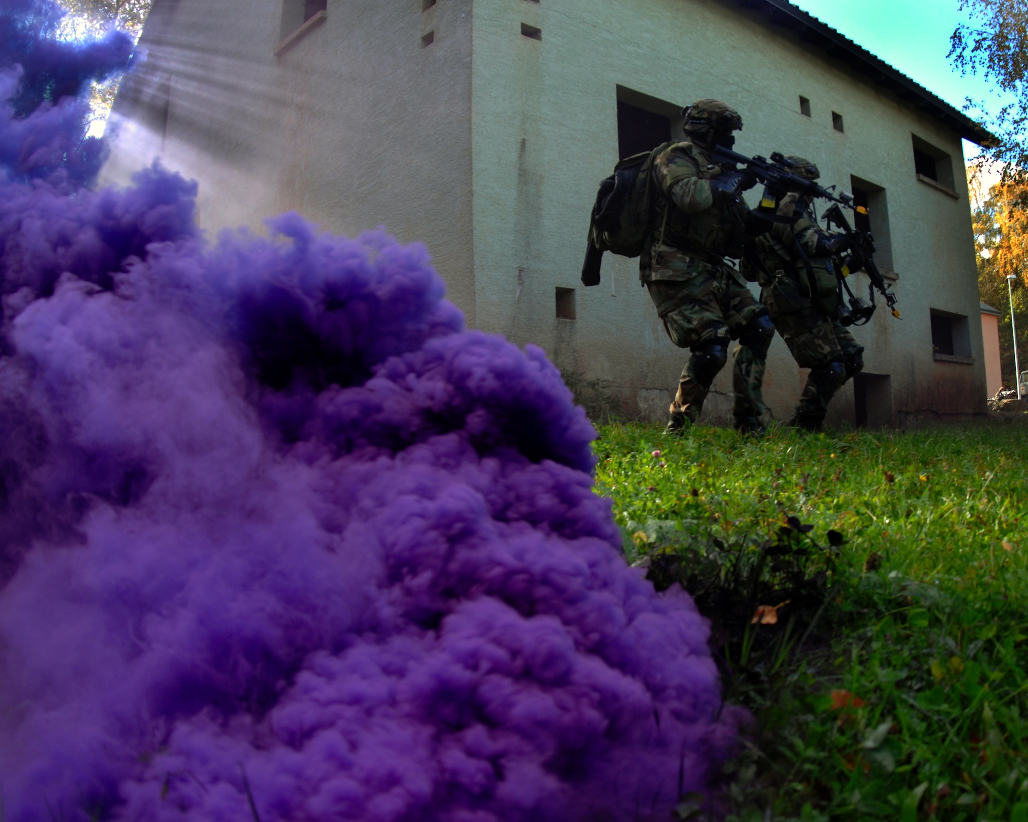 Senior Airman Marques Lipford (left) and Staff Sgt. Lindsy Lyons, from the 31st Security Forces Squadron at Aviano Air Base, Italy, move swiftly through a purple haze so as not to be seen by the enemy during Military Operation and Urban Terrain exercise at Baumholder, Germany Oct. 20. The exercise taught security forces Airmen techniques to use when raiding and searching buildings and houses. (U.S. Air Force photo/Airman 1st Class Kenny Holston)