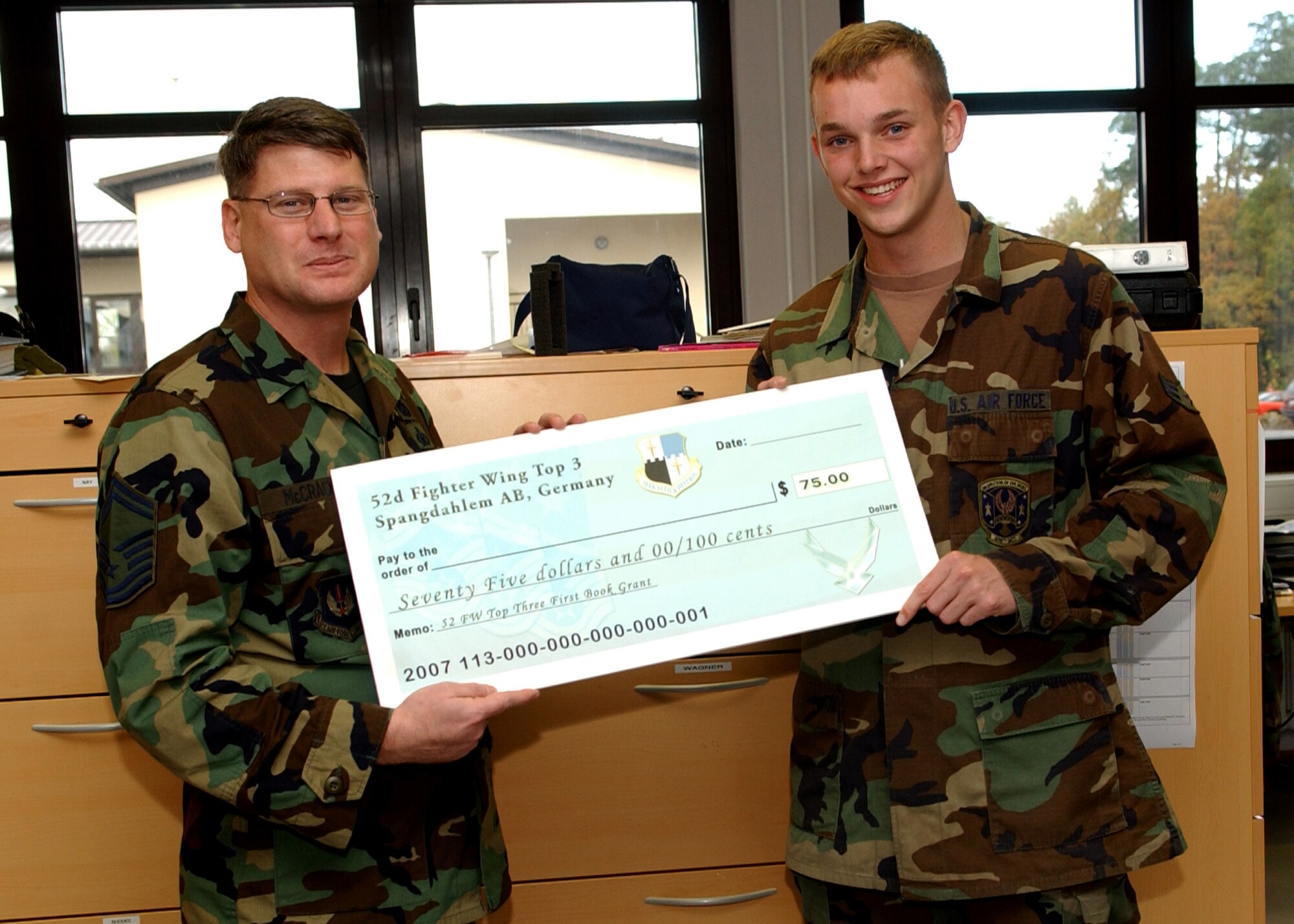 SPANGDAHLEM AIR BASE, Germany -- Senior Master Sgt. Patrick McCracken, 52nd Fighter Wing Top 3 Education Committee, presents Airman 1st Class Corey Wagner, 606th Air Control Squadron, with a First Book Grant of $75. The First Book program was initiated to encourage Airmen to continue their education. (U.S. Air Force photo/Airman 1st Class Allen Pollard)                                                     