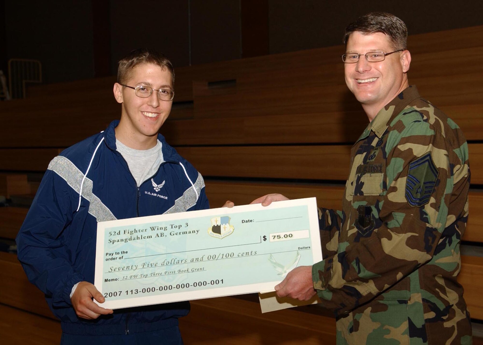 SPANGDAHLEM AIR BASE, Germany -- Senior Master Sgt. Patrick McCracken, 52nd Fighter Wing Top 3 Education Committee, presents Airman 1st Class Jonathan Webber, 52nd Communications Squadron, with a First Book Grant of $75. The First Book program was initiated to encourage Airmen to continue their education. (U.S. Air Force photo/Airman 1st Class Allen Pollard)                                                     