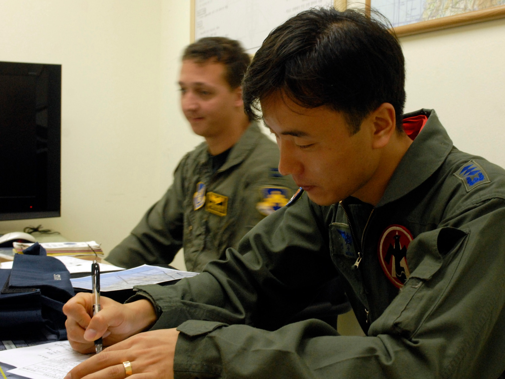 JUNGWON AIR BASE, South Korea -- Republic of Korea Air Force Capt. Sang-su Jung, foreground, makes notes as U.S. Air Force Capt. Michael McCarthy gives a pre-flight brief during the Buddy Wing program here Oct. 24.  Captain Jung is a pilot assigned to the 161st Fighter Squadron and Capt. McCarthy is a pilot assigned to the 80th Fighter Squadron, Kunsan Air Base, South Korea.  The Buddy Wing program is a way for U.S. Air Force and Republic of Korea Air Force Airmen to develop teamwork, exchange ideas and improve war time tactics.  (U.S. Air Force photo/Senior Airman Steven R. Doty)