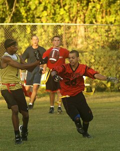 Larico Ellis (left), 437th Medical Group, bobbles the ball while Bradlon Barge, 437th Aircraft Maintenance Squadron, intercepts it during an intramural flag football game Tuesday night on base. Bradlon would have scored a touchdown if his team had not committed a holding foul. (U.S. Air Force Photo/Airman 1st Class Nicholas Pilch)