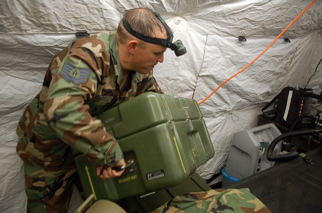 Air Force Tech. Sgt. Bruce Graybill, noncommissioned officer in charge of the Joint Task Force-Bravo Medical Element Mobile Surgical Team, carries a case of medical equipment while setting up an MST tent in an empty field here Oct. 18.  The team set up the mobile operating room at night to practice setting up in limited visibility.  (U.S. Air Force photo by Staff Sgt. Austin May)