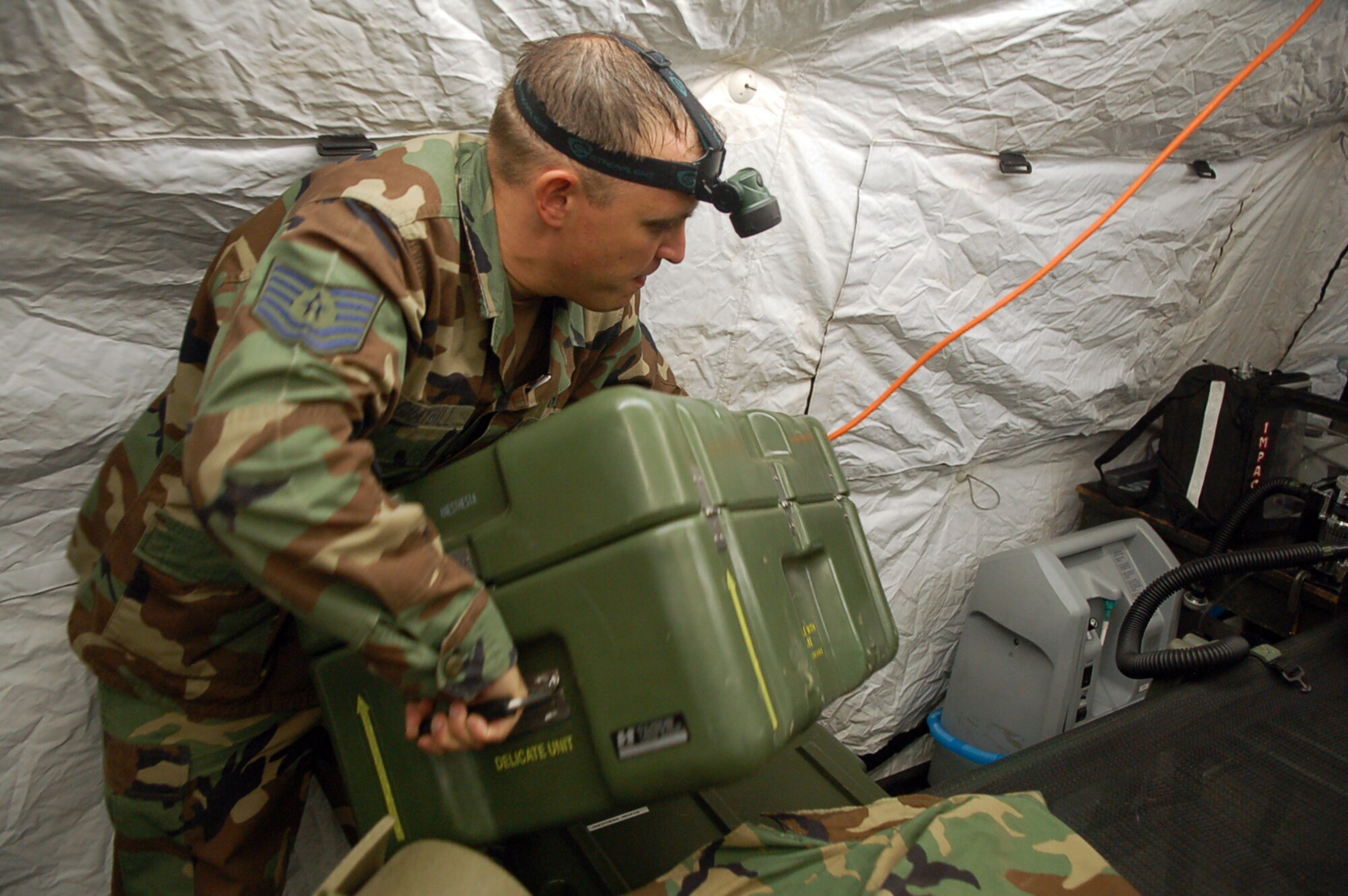 Air Force Tech. Sgt. Bruce Graybill, noncommissioned officer in charge of the Joint Task Force-Bravo Medical Element Mobile Surgical Team, carries a case of medical equipment while setting up an MST tent in an empty field here Oct. 18.  The team set up the mobile operating room at night to practice setting up in limited visibility.  (U.S. Air Force photo by Staff Sgt. Austin May)