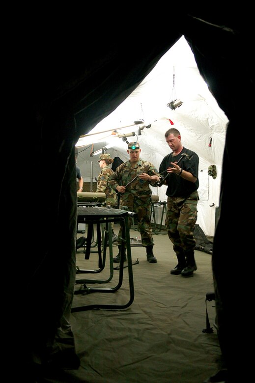 Working by the only light in a sea of darkness, Air Force Tech. Sgt. Bruce Graybill and Master Sgt. Troy Himes, Joint Task Force-Bravo Medical Element, work to set up a Mobile Surgical Team tent in an empty field here Oct. 18.  The team set up the mobile operating room at night to practice setting up in limited visibility.  (U.S. Air Force photo by Staff Sgt. Austin May)