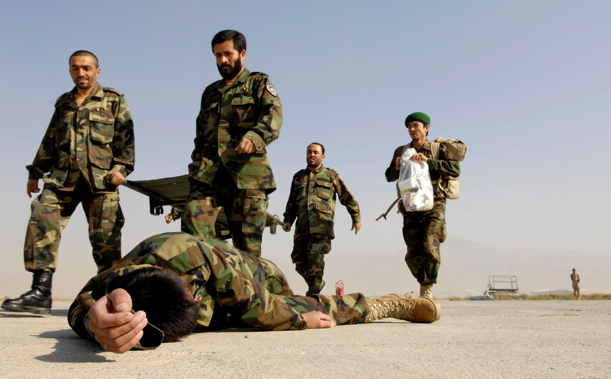 An Afghan national army air corps medical litter crew and medic come to the aid of a downed ANA soldier during an Oct. 20 exercise at Kabul International Airport, Afghanistan. The exercise, observed by U.S. Air Force Airmen, and was designed to help train and keep the medical staff here proficient in the skills needed to do their jobs. (U.S. Air Force photo/Staff Sgt. Brian Ferguson)
