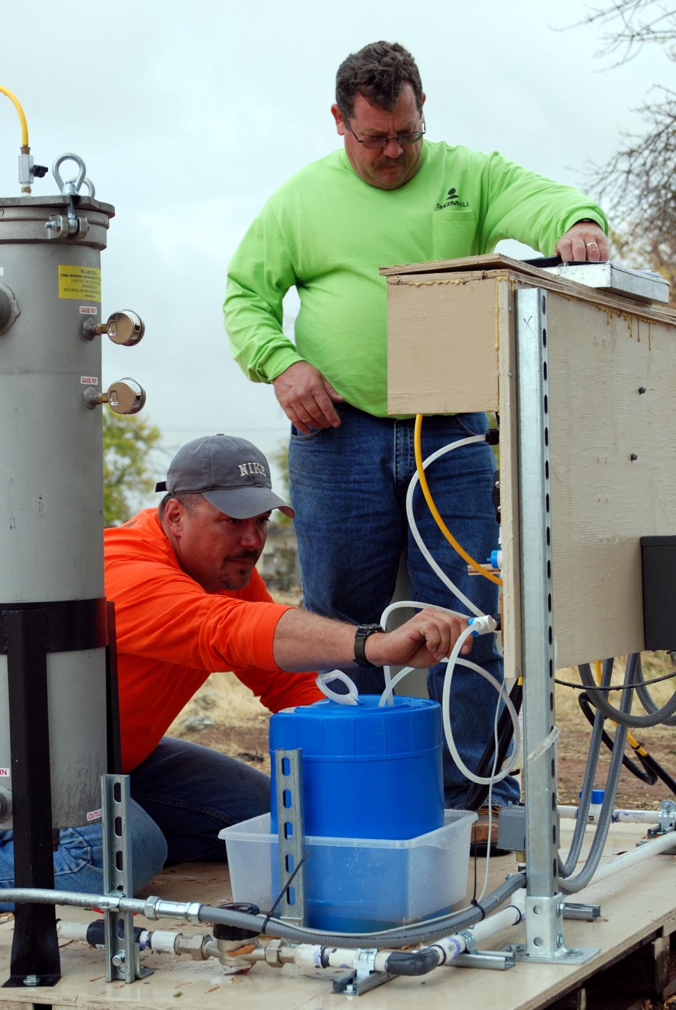 Kevin Roberts (left) and Chris Goodrich check the calibration of bleach injection pumps and collect data from pump controllers at a treatment skid Oct. 16 at Site 31 at Beale Air Force Base, Calif. Mr. Roberts is a CH2M HILL environmental technologist, and Mr. Goodrich is a CH2M HILL remedial treatment systems construction manager. (U.S. Air Force photo/Airman 1st Class Robert Biermann)
