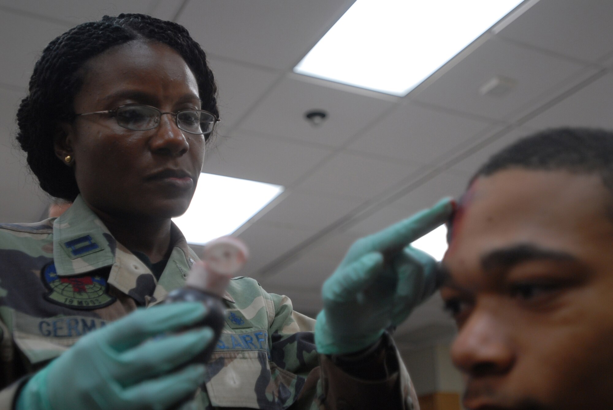 Capt. Mickaelle Germain, 18th Medical Operations Squadron, applies moulage to the head of Airman Basic Lemar Mayberry, 18th Component Maintence Squadron, to simulate a wound during an exercise scenario at Kadena Air Base, Japan, Oct. 24, 2007.  Moulaged "victims" provide more realism to exercise scenarios. The Airmen are supporting training missions based on real-world scenarios as part of Local Operational Readiness Exercise Beverly High 08-1. (U.S. Air Force photo/Senior Airman Darnell T. Cannady)