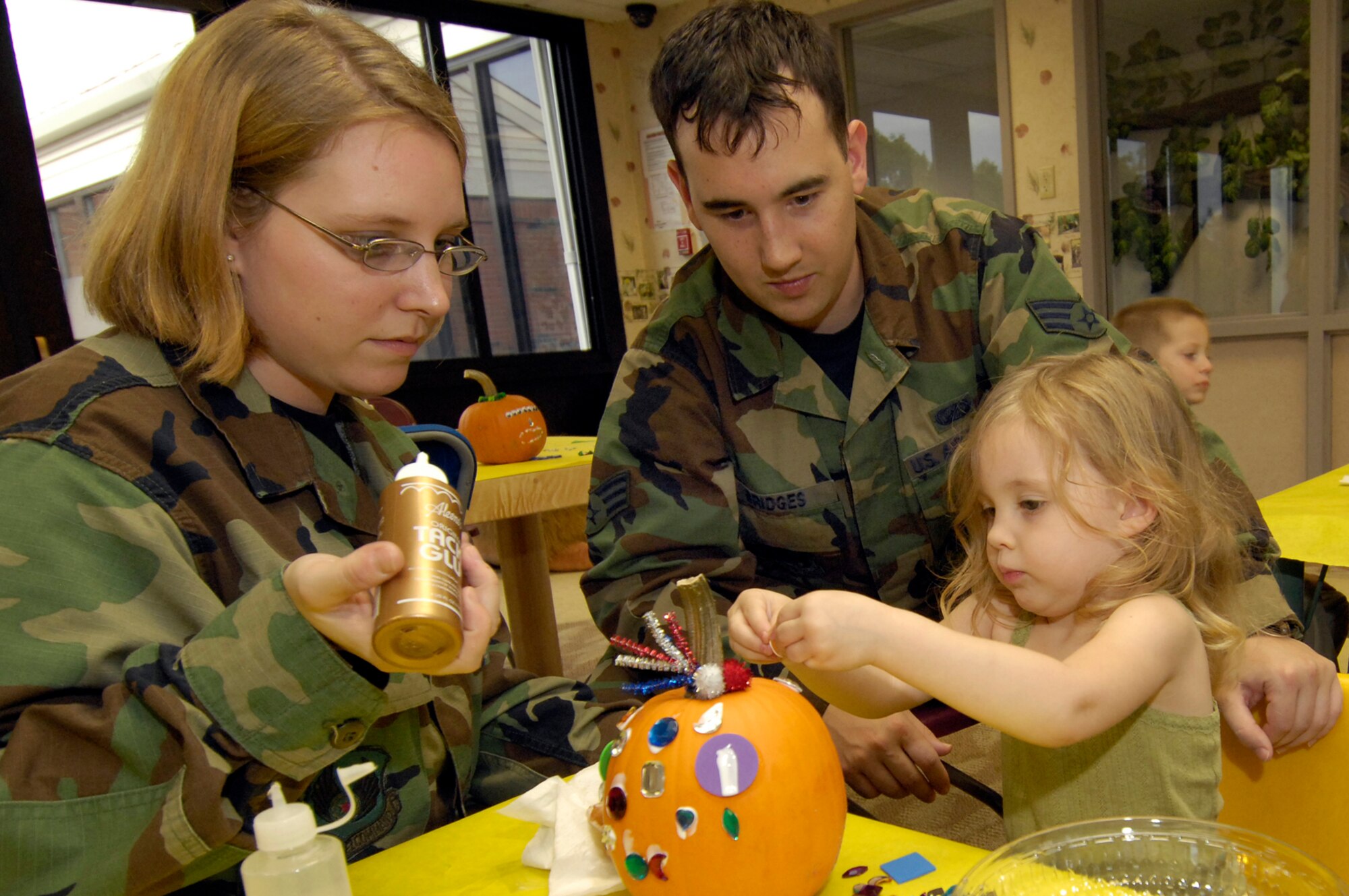HANSCOM AFB, Mass. – Senior Airman Jacqueline Bridges (left) and Senior Airman Jeremy Bridges help their daughter Alyssa decorate a pumpkin during the Child Development  Center’s pumpkin decorating activity for families enrolled at the center. The CDC offers many opportunities throughout the year for families to take part in activities such as this. The next activity will take place on Nov. 1 from 3 to 5 p.m. Volunteers are asked to take part in a playground cleanup at the CDC. (U.S. Air Force photo by Mark Wyatt)

