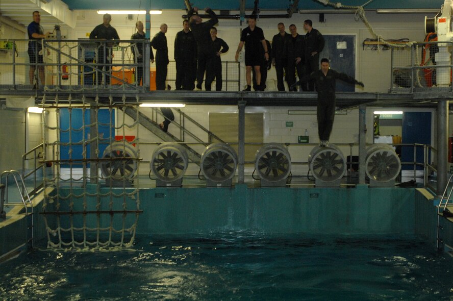 Students jump from a ledge 5 feet above the wave pool, a traditional way of ending the water survival refresher course held at Lowestoft College, Maritime and Offshore Facilities. During initial water survival training Airman are taught how to apply first aid in an aquatic environment, ocean ecology and equipment maintenance – and to use aquatic survival gear. (U.S. Air Force photo by Senior Airman Teresa M. Hawkins)
