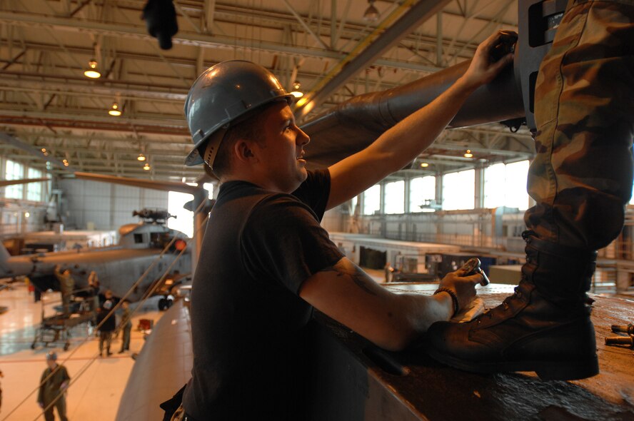 Crew chief, Airman 1st Class Chris Ollivier, from the 352nd Maintenance Squadron, Helicopter Maintenance Unit, RAF Mildenhall, England, removes one of eight bolts holding a 350 pound rotor blade from one of five MH-53M Pave Low IV Helicopters assigned to the 21st Special Operations Squadron, Oct. 02, 2007. Once the tear down process is complete, it usually takes an average two days; the helicopters will be transported to the Aerospace Maintenance and Regeneration Group in Tucson, Ariz., commonly known as the 'Boneyard.' All Pave Low helicopters in the Air Force inventory are due to be grounded by October 2008. (U.S. Air Force photo by Tech. Sgt. Tracy L. DeMarco)