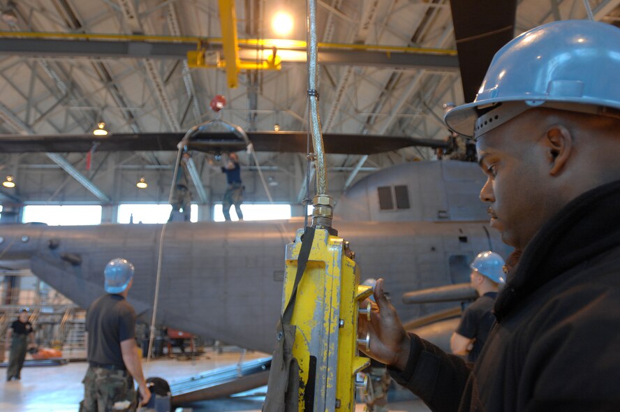 Manning the overhead hoist, Tech. Sgt. Michael Barns, an avionics specialist assigned to the 352nd Maintenance Squadron, Helicopter Maintenance Unit, RAF Mildenhall, England, works closely with two other team members positioned on the tail section of one of five MH-53M Pave Low IV Helicopters assigned to the 21st Special Operations Squadron, to gently lift each blade to remove tension before the eight bolts that hold it in-place can be removed, Oct. 02, 2007. Once the tear down process is complete, it usually takes an average two days; the helicopters will be transported to the Aerospace Maintenance and Regeneration Group in Tucson, Ariz., commonly known as the 'Boneyard.' All Pave Low helicopters in the Air Force inventory are due to be grounded by October 2008. (U.S. Air Force photo by Tech. Sgt. Tracy L. DeMarco)