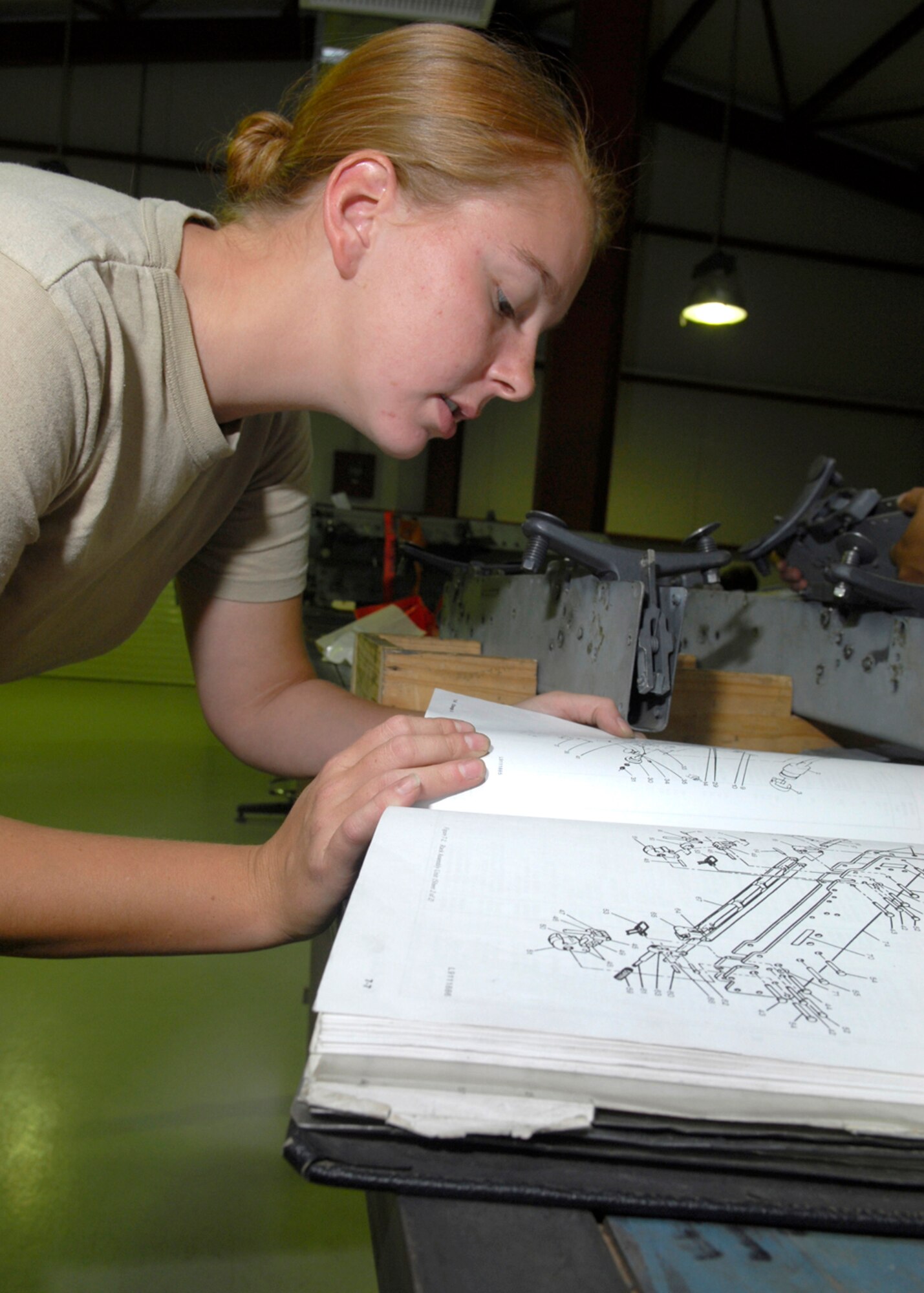 BALAD AIR BASE, Iraq -- Airman 1st Class Melissa Cunningham, 332nd Expeditionary Maintenance Squadron, refers to a technical order to ensure she is properly assembling a Triple Ejector Rack-9A. The technical order gives guidance for all equipment being maintained by personnel. Airman Cunningham is currently deployed from Spangdahlem Air Base, Germany. (U.S. Air Force photo/Staff Sgt. Joshua Garcia)