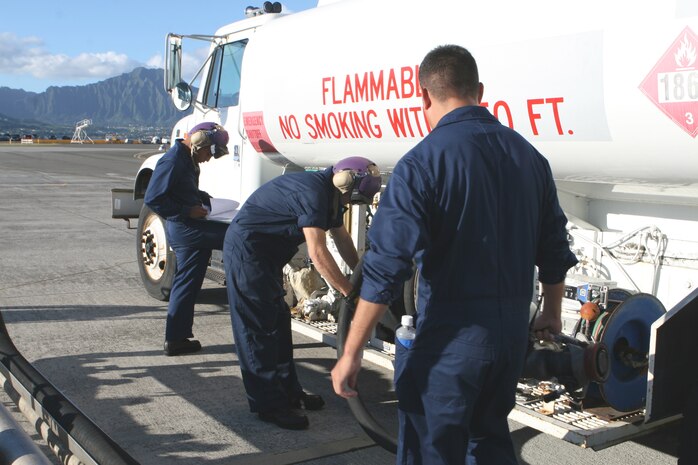 Petty Officer 1st Class Joseph Macias holds the hose while Cpl. Rober Rakentine wraps it back up after filling the truck Wednesday. Sergeant Milton Gamez documents how much fuel is in the tank before delivering it to aircraft.