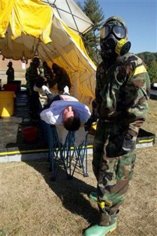 Lance Cpl. Joe Pesina (right), decontamination line litter bearer, Company B, Chemical Biological Incident Response Force, II Marine Expeditionary Force, assists a casualty on the decontamination line at training exercise Capital Shield '07 at Lorton, Va., on Oct. 24. The casualty will be examined again for any remaining contaminants that may not have been washed off.