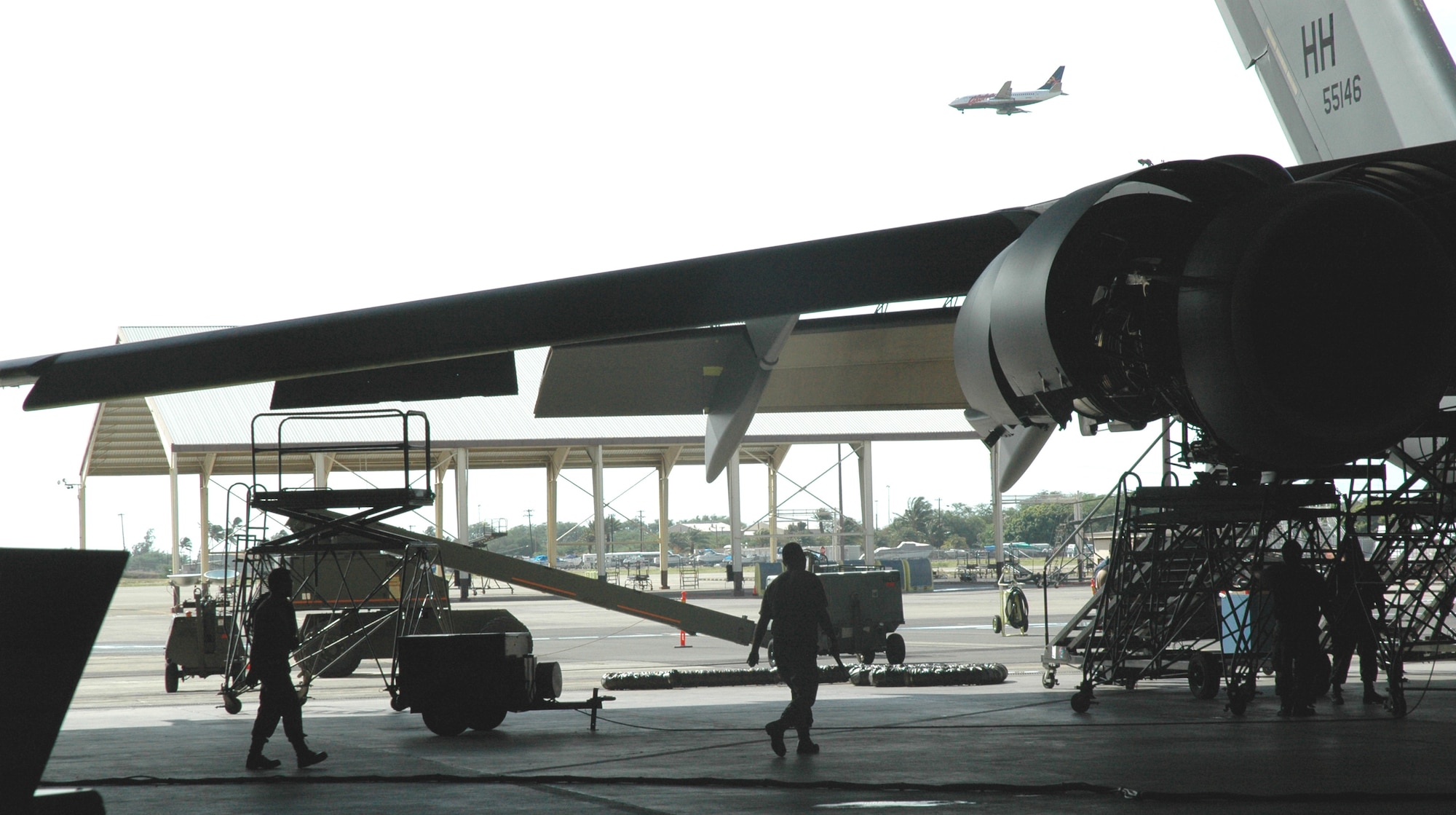 The 154th Maintenance Squadron, Hawaii Air National Guard, swarm over a C-17 which dwarfs the World War II era hangar it sits in. The C-17s are too big to fit all the way inside the hangars with the doors closed, and historic preservation prevents modification of the hangars. Aircraft inspections have to be conducted at the wash rack outside the hangar, weather permitting. (US Air Force photo/Master Sgt Ellen L Hatfield)