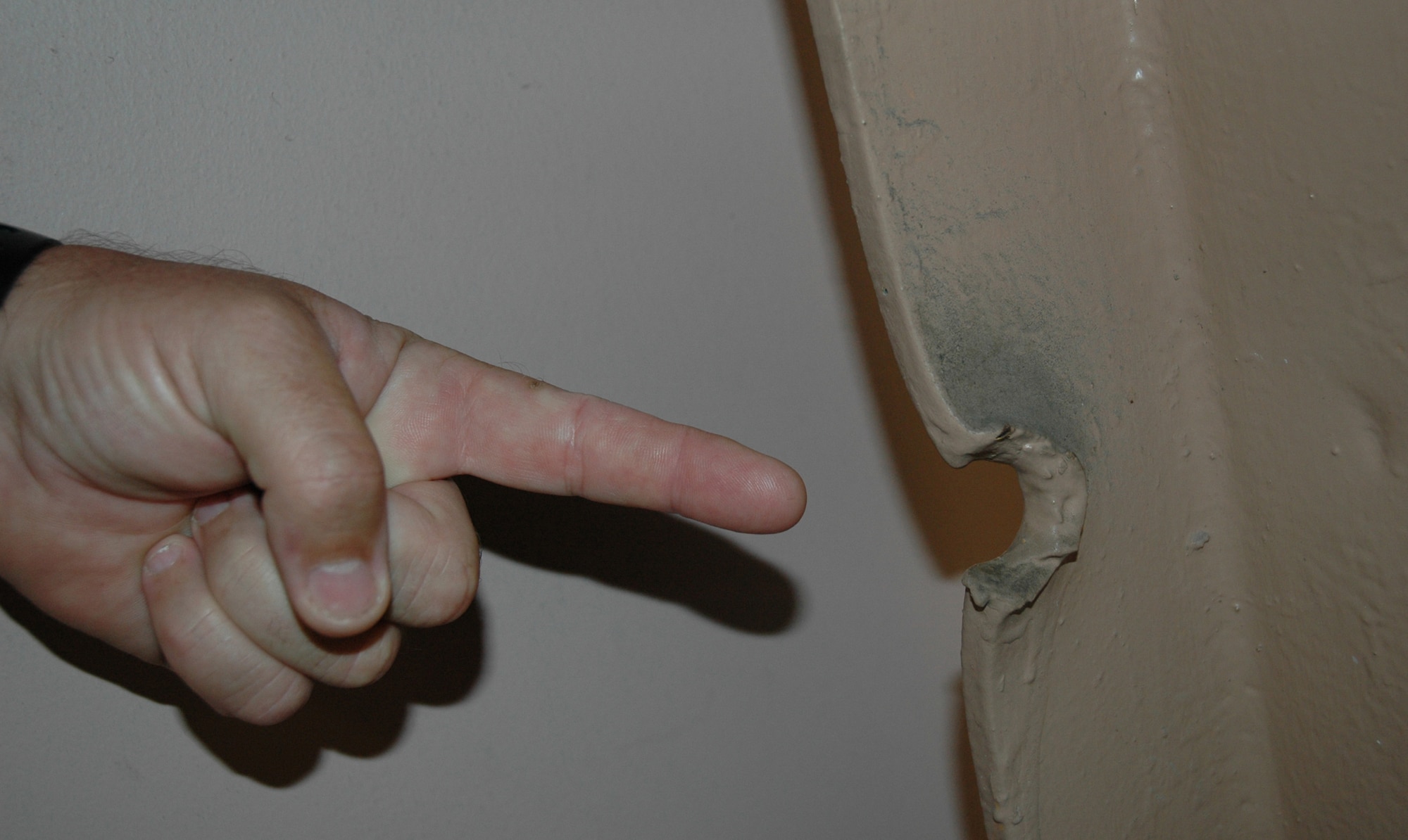 Master Sgt Gene Graye, 940th Maintenance Group electro environmental technician, points to the path a Japanese bullet took during the attack on Pearl Harbor, Hawaii, Dec. 7, 1941. On the day that launched the U.S. into World War II, Japanese aircraft strafed the hangars on Hickam Air Force Base. The remnants of that attack have been preserved for history. Sergeant Graye was part of a maintenance team that spent from Sept. 14-28, 2007, helping the 154th Maintenance Squadron, Hawaii Air National Guard, with maintenance on their fleet of KC-135s and the active duty's newest airlifter, the C-17. 