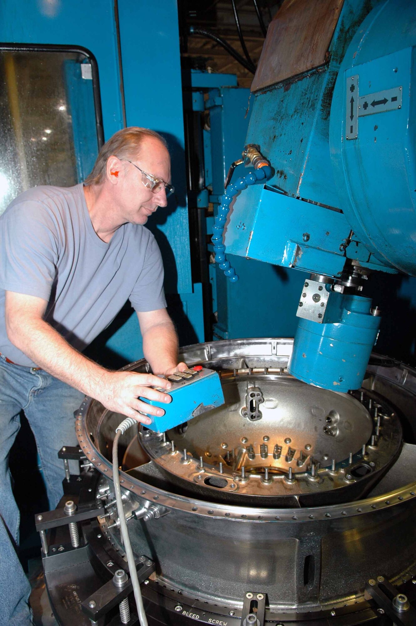 Mike Kraus, a machinist with the 547th Propulsion Maintenance Squadron, makes adjustments on a five-axis milling machine prior to working on a F119 intermediate compressor. (Air Force photo by Ron Mullan)