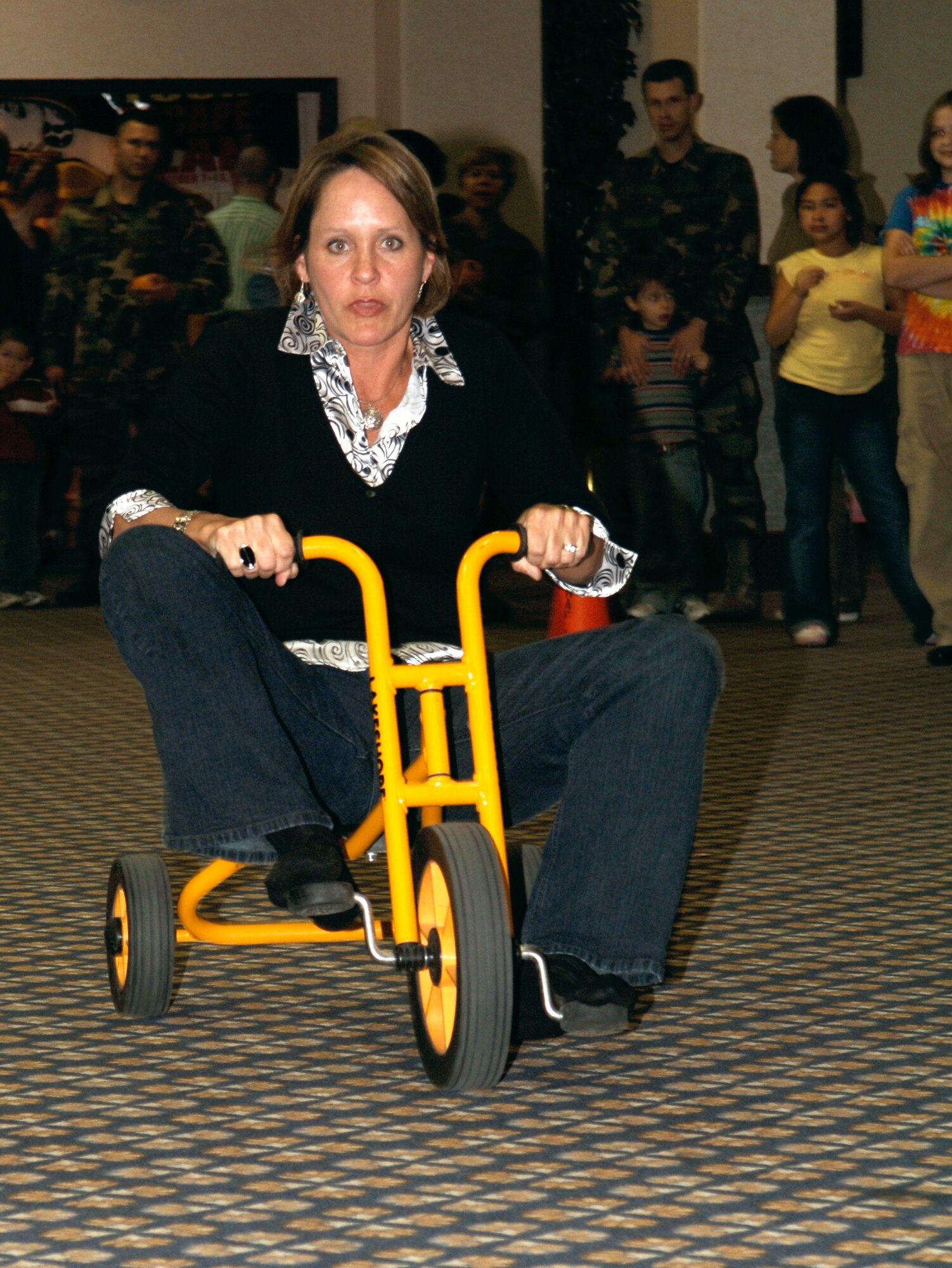 FAIRCHILD AIR FORCE BASE, Wash. -- Kelly Fuller, wife of Col. Van Fuller, 92nd Mission Support Group commander, races a tricycle during the 92nd MSG Night at the Club held at Club Fairchild on Oct. 19. The tricycle race was one of the many activities held during the 70s-themed night. (U.S. Air Force photo / Senior Airman Chad Watkins)