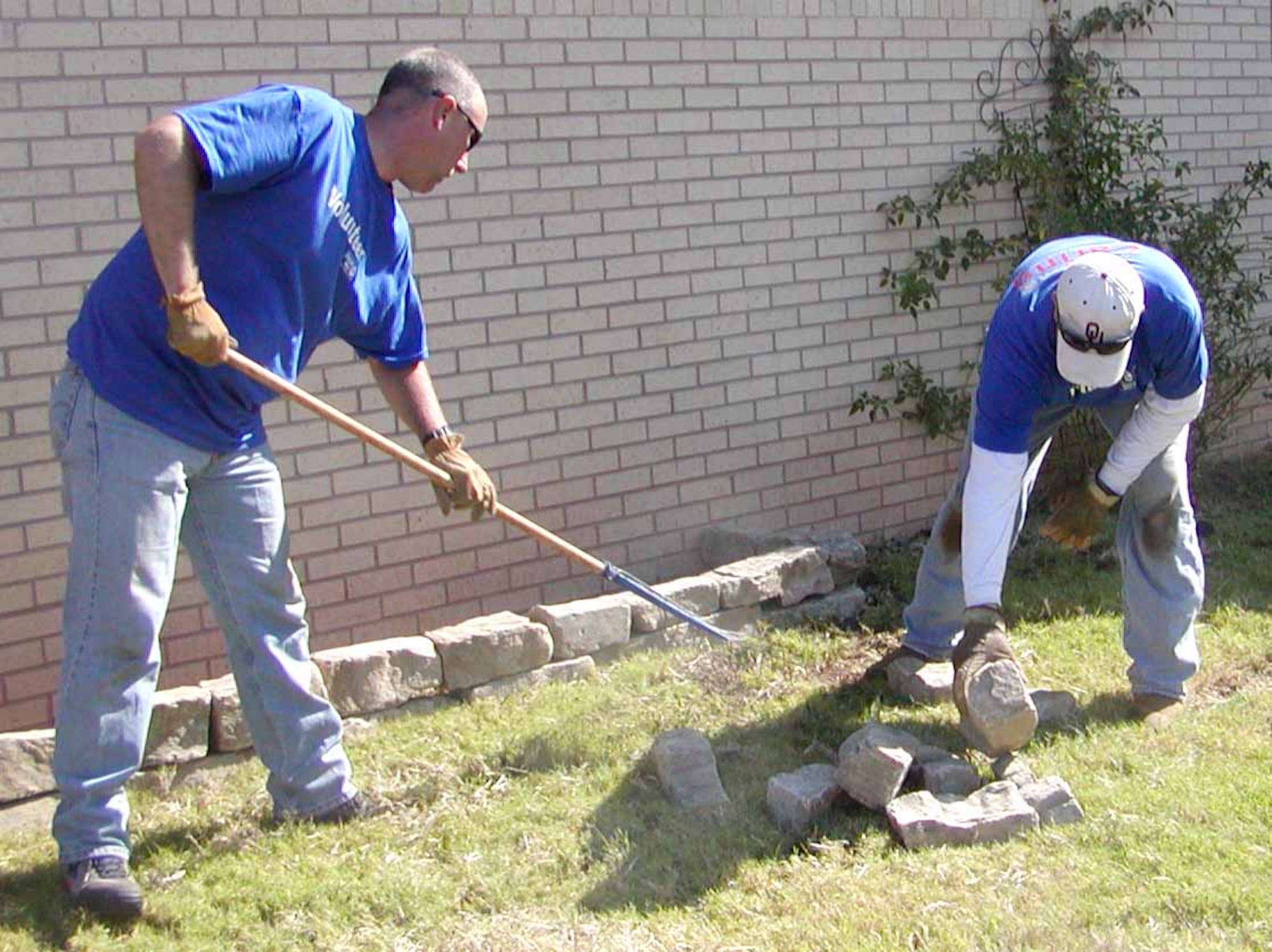 Master Sgt. Michael Perry and Randy Childress complete the cleanup work for a new flower bed on the front side of the youth center. (Air Force photo by Debbie Tapparo)