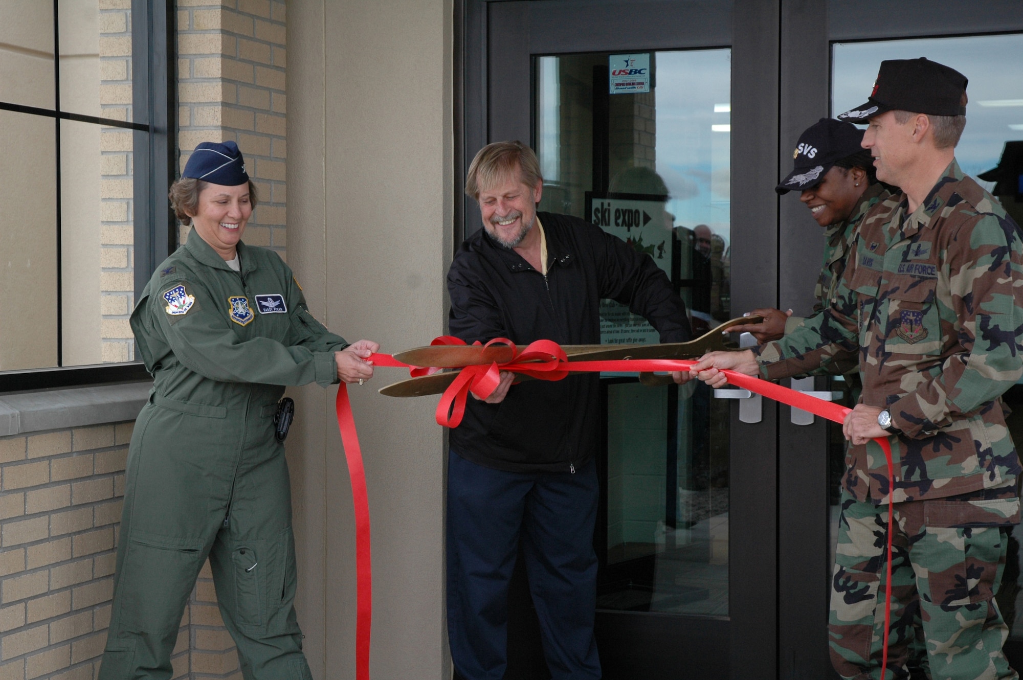 Col. Sandy Finan, 341st Space Wing commander, and Col. Roderick Davis, 341st Mission Support Group commander, hold the ribbon while Maj. Rosalyn Walker, 341st Services Squadron commander and Bryon Mullett, manager of the Aces High Bowling Center, cut the ribbon at the re-opening of the bowling center Oct. 19. The center received a major facelift to the exterior of the building during the past seven months. (U.S Air Force photo/Airman 1st Class Emerald Ralston)