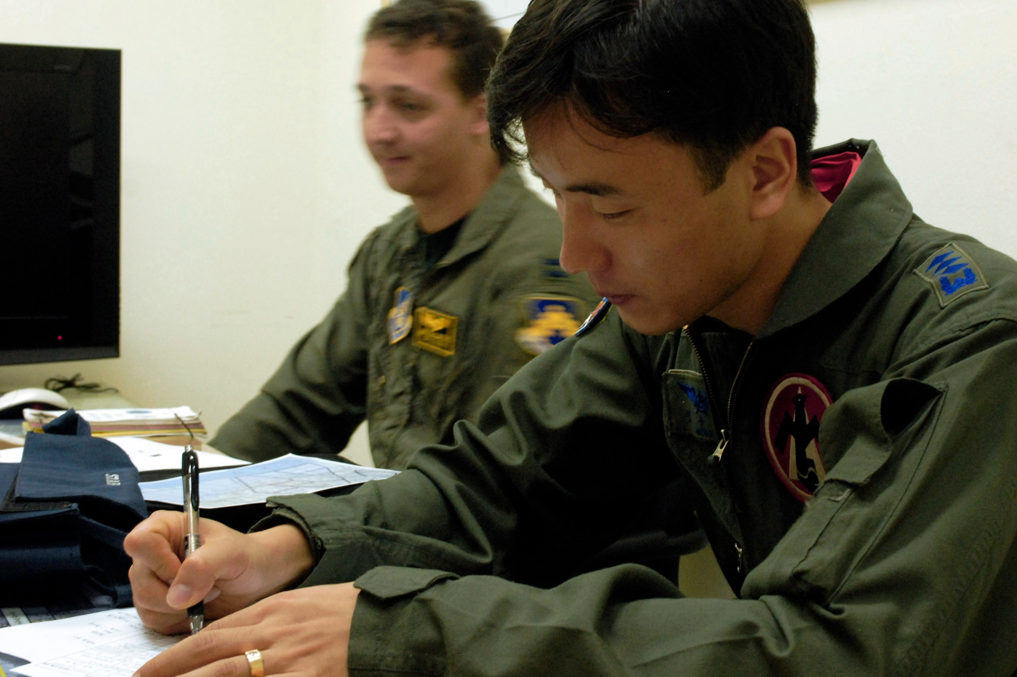 South Korea air force Capt. Sang-su Jung (foreground) takes notes as U.S. Air Force Capt. Michael McCarthy gives a pre-flight brief during the Buddy Wing program at Jungwon Air Base Oct. 24. Captain Jung is a pilot assigned to the 161st Fighter Squadron and Capt. McCarthy is a pilot assigned to the 80th Fighter Squadron, Kunsan Air Base, South Korea. The Buddy Wing program is a way for U.S. Air Force and South Korea air force to develop teamwork, exchange ideas and improve war time tactics. (U.S. Air Force photo/Senior Airman Steven R. Doty) 
