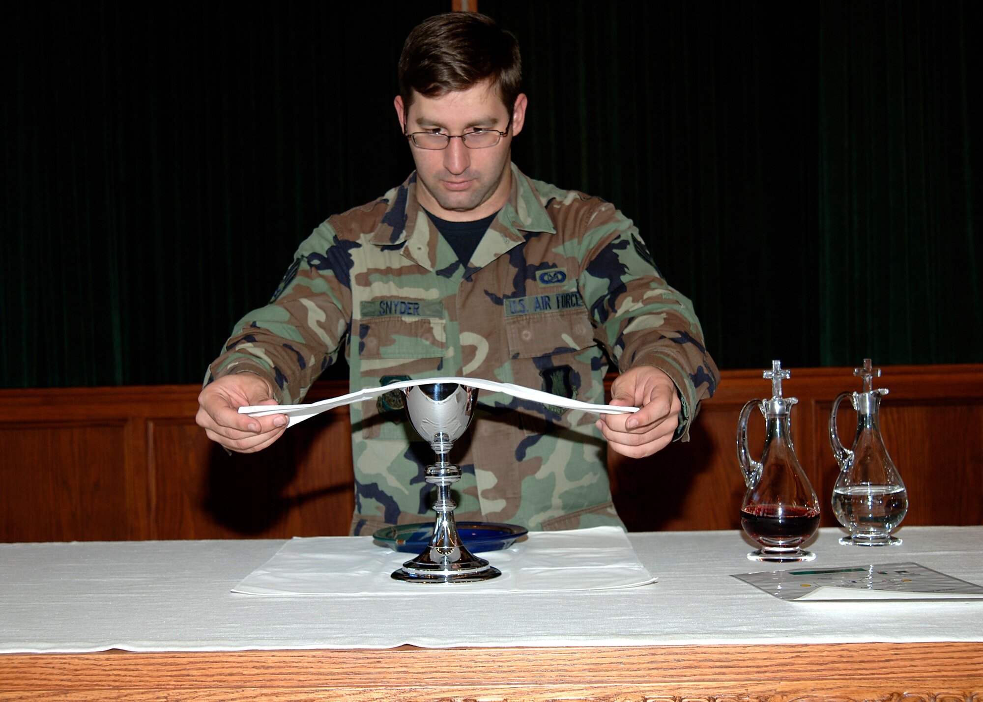 MCCONNELL AIR FORCE BASE, Kan. -- Senior Airman Paul Snyder, chaplain’s assistant, prepares the altar at the base chapel for the communion during the evening’s Episcopal Service Oct. 23. Senior Airman Snyder is a Chaplain Assistant, and his daily job consists of setting up for services, being knowledgeable on all of the different faiths, and providing aid to the many tasks and requirements that chaplains undergo. (Photo by Airman First Class Justin Shelton) 