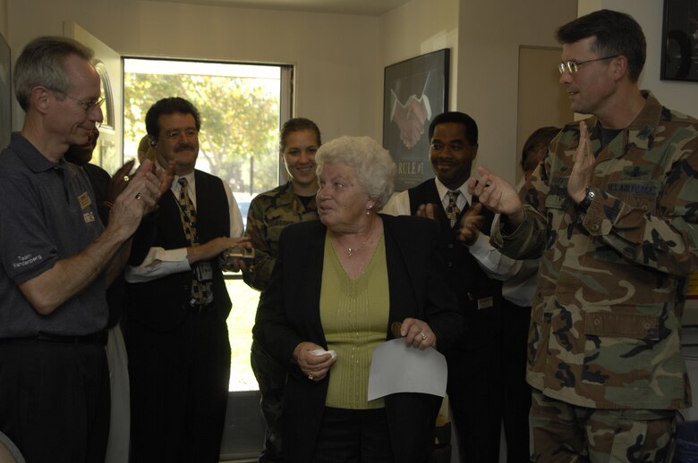 Emilie Acklen, former Vandenberg AFB housekeeping room attendant, recieves the applause of Col. Benjamin Huff, 30th Mission Support Group commander, and other 30th MSG members, at her retirement ceremony here on Oct. 19. Ms. Acklen has been a room attendant at Vandenberg since 1969.