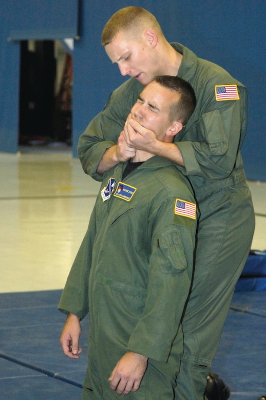 Staff Sgt. David Wood demonstrates how to apply pressure point techniques during the hand-to-hand combat exhibition on Senior Airman Aaron Lawrence, during the Ravens security demonstration inside hangar four on Sept. 25. The Raven Team's mission is to provide security for all special air missions carrying the President, Vice President and other senior government leaders during their official travel. They are both assigned to the 316 SFS Ravens team.(US Air Force/A1C Renae Kleckner)