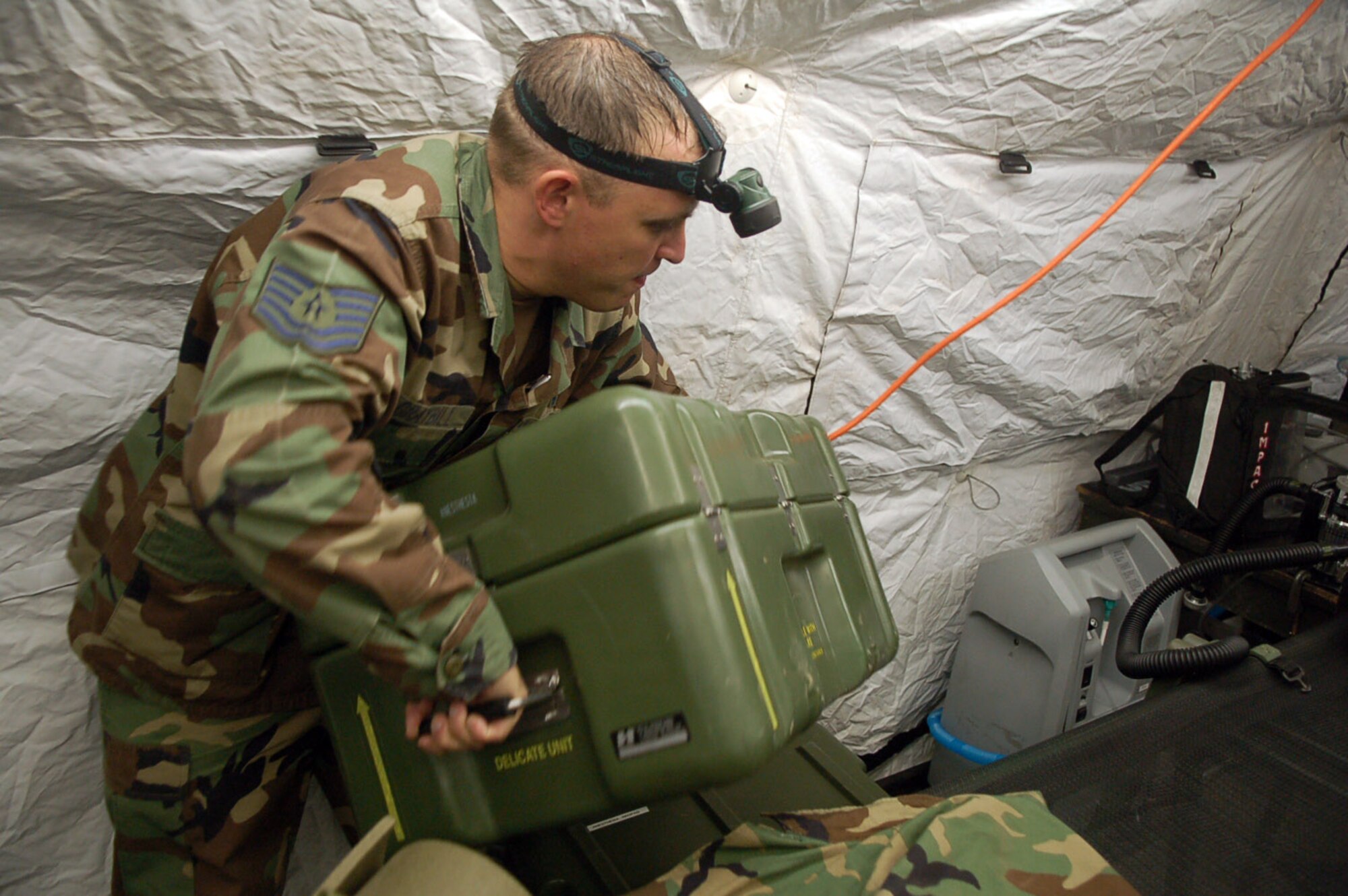 Tech. Sgt. Bruce Graybill carries a heavy case filled with medical equipment while setting up a mobile surgical tent in an empty field at Soto Cano Air Base, Honduras, Oct. 18. The Joint Task Force-Bravo Medical Element Mobile Surgical Team team built up the operating room at night to practice setting up in limited visibility. Sergeant Graybill is NCO in charge of the team. (U.S. Air Force photo/Staff Sgt. Austin May) 