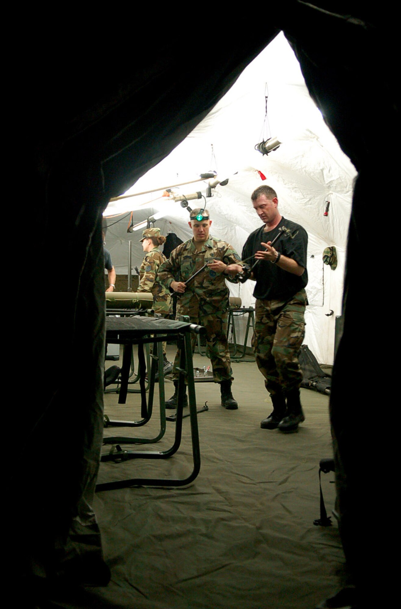 Working by the only light in a sea of darkness, Tech. Sgt. Bruce Graybill and Master Sgt. Troy Himes set up a mobile surgical team tent in an empty field at Soto Cano Air Base, Honduras, Oct. 18. The team set up the mobile operating room at night to practice setting up in limited visibility. The NCOs are members of the Joint Task Force-Bravo Medical Element. (U.S. Air Force photo/Staff Sgt. Austin May) 

