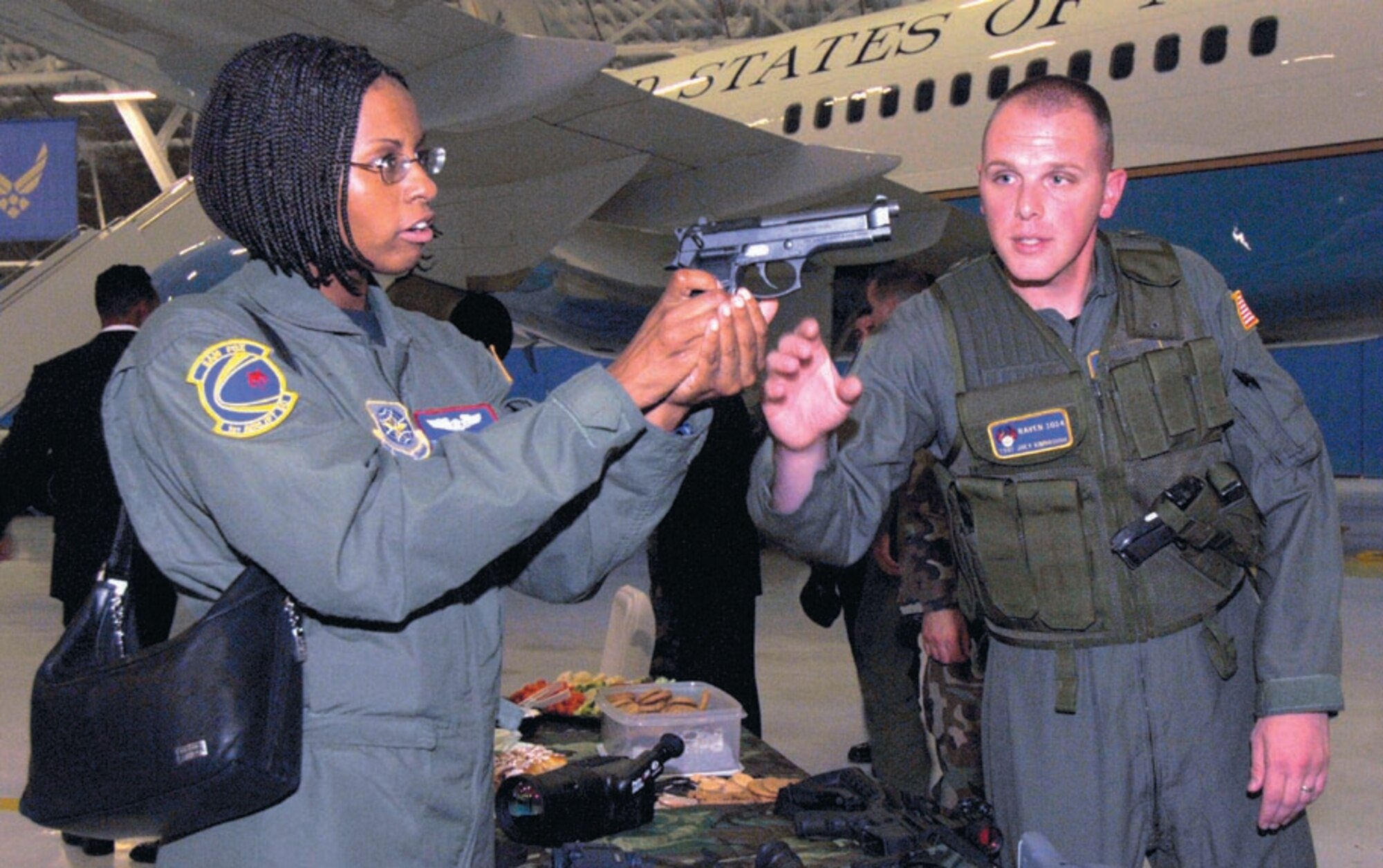 Tech. Sgt. Joey Kimbrough, 316th Security Forces Squadron Raven, explains the operation of a 9mm weapon to Staff Sgt. Cheneldrea Moore, 1st Helicopter Squadron, during a hands-on demonstration during the Ravens security demonstration inside hangar four on Sept. 25. The Raven Team's mission is to provide security for all special air missions carrying the President, Vice President and other senior government leaders during their official travel. (US Air Force/SSgt Suzanne Day)