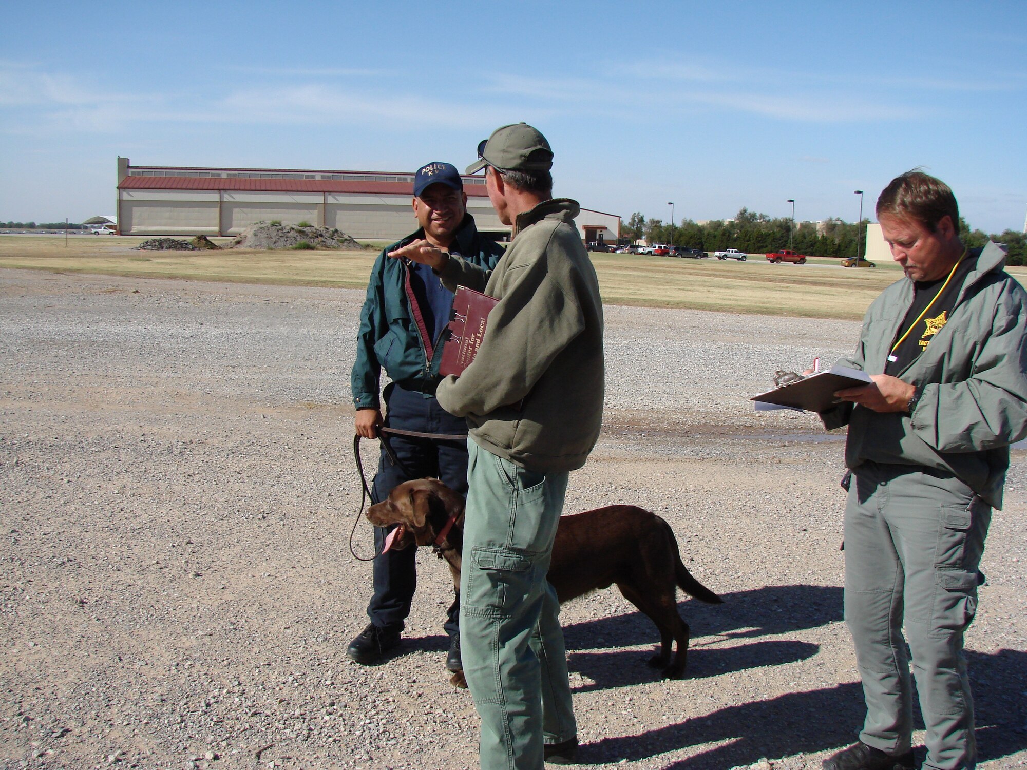 National Police Canine Association Instructor Paul Koinig debriefs Explosives Officer Tad Valdez of the Harris County Constable's office in Texas, while NPCA instructor Ray Ruby evaluates the performance of  20-minute search for explosives with police canine Charlie of the same office. 