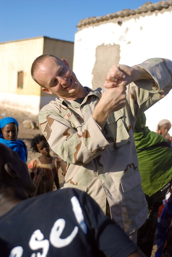 Master Sgt. Dennis Hoffman gives an impromptu magic show Oct. 23 for the children of Nagad, Djibouti. Sergeant Hoffman is a drummer with the U.S. Central Command Air Force's Expeditionary Band Live Round. The band is touring Djibouti to perform a series of morale and community outreach concerts. (U.S. Army photo/Sgt. Charles Siler) 
