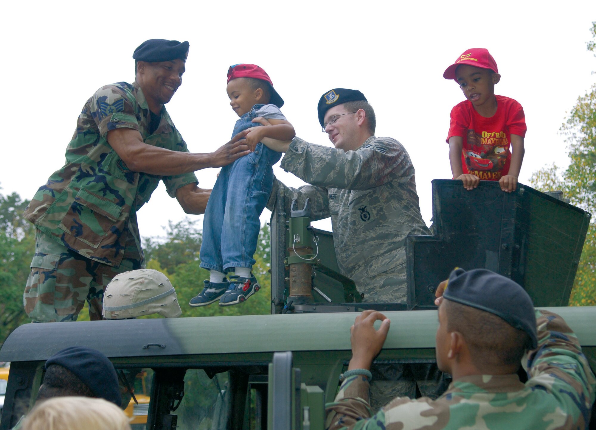 Staff Sgt. Willie Broadnax, 316th Security Forces Squadron Military Working Dog handler, and staff Sgt. Christopher West, 316 SFS Security Response Team leader, give a tour of a humvee to Christopher and Nicholas Brown during Truck Day at Corkran United Methodist Preschool, Temple Hills, Md. Oct. 5. (US Air Force/A1C Renae Kleckner)