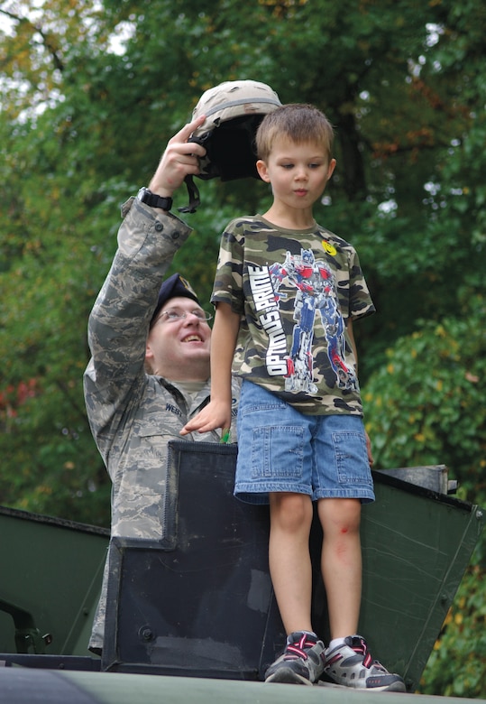 Staff Sgt. Christopher West, 316th Security Forces Squadron, places a Kevlar helmet on James O'Leary, son of Capt. Steven O'Leary, Air Force Office of Analysis, Assessments and Lessons Learned, during Truck Day at Corkran Preschool, Temple Hills, Md. Oct. 5. (US Air Force/A1C Renae Kleckner)
