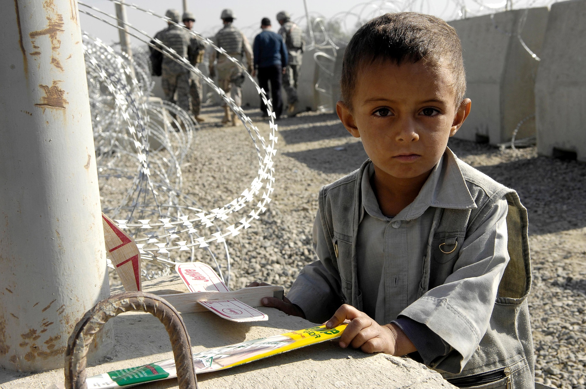A young Afghan boy waits outside the entry control point of Kabul International Airport, Oct 22, after receiving a toy plane from a group of Air Force members. The toy planes were given out along with soccer equipment to a group of local children from the Kabul Youth Soccer League . The equipment was donated from businessmen and supporters from Tennessee, Georgia and California. (U.S. Air Force photo/Staff Sgt. Brian Ferguson)