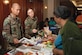 Senior Airmen Giovanni Espiritu and Zorryanna Karabin, 79th Medical Support Squadron, provide Emma  Head, wife of Master Sgt. (red.) Alve D. Head, with nutrition information and samples during the Retiree Appreciation Day luncheon Oct. 20. (US Air Force/TSgt Jason Edwards)