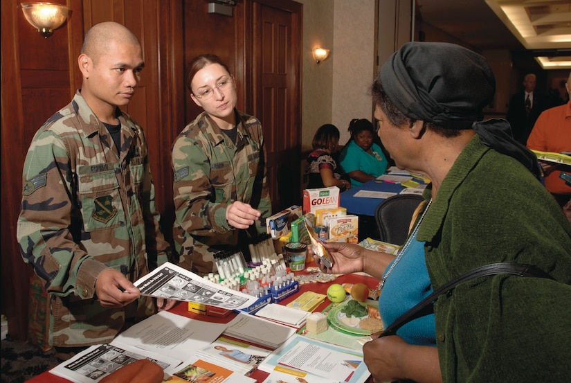 Senior Airmen Giovanni Espiritu and Zorryanna Karabin, 79th Medical Support Squadron, provide Emma  Head, wife of Master Sgt. (red.) Alve D. Head, with nutrition information and samples during the Retiree Appreciation Day luncheon Oct. 20. (US Air Force/TSgt Jason Edwards)