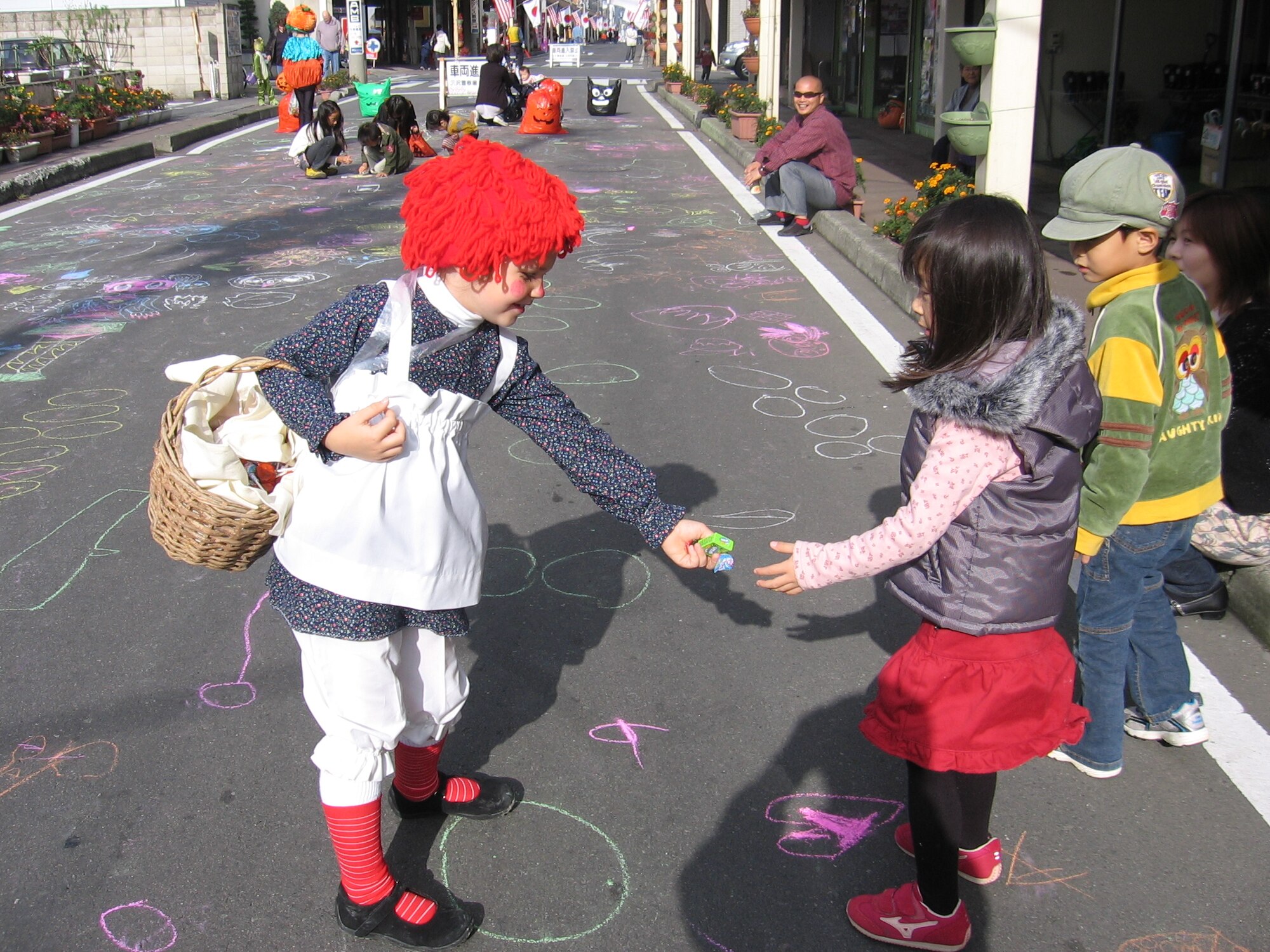 MISAWA AIR BASE, Japan -- Caitlin Slater, daughter of Chief Warant Officer 2 Jason Slater of the 403rd Military Intelligence, shares her candy with a Japanese girl at the Misawa Halloween Festival Oct. 20, 2007. The festival, held on White Pole Road, featured a costume contest with more than 200 entries and a costume parade. Caitlin, in her Raggedy Ann costume, placed fourth in the costume contest, winning 5000 yen. Bags of treats were given to all participants and Japanese trick-or-treating was held with the local businesses. (Photo by Kelly Slater)