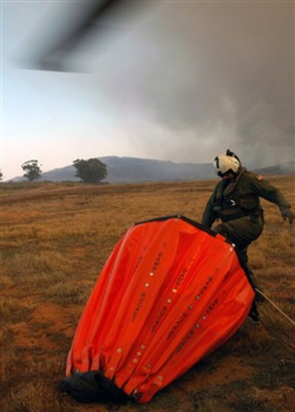 U.S. Navy Chief Aviation Electronics Technician Rexford Sackett kicks open a stubborn 420-gallon capacity bucket in San Diego, Calif., on Oct. 23, 2007.  Sackett is assigned to Helicopter Sea Combat Squadron 85 that has teamed up with the San Diego California Department of Forestry and Fire Protection to help put out the wildfires blazing across Southern California.  