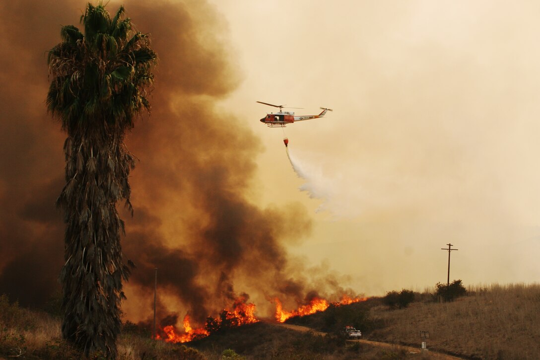 In an effort to control and contain the fires on Marine Corps Base Camp Pendleton, California, a UH-1N Search and Rescue Unit helicopter, stationed out of Naval Air Station Fallon, releases a large amount of water onto the local fires, October 24, 2007.